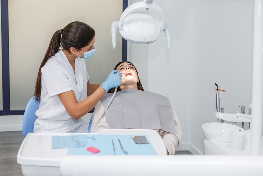 A dentist examining her female patient’s teeth